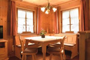 ein Esszimmer mit einem Tisch, Stühlen und Fenstern in der Unterkunft Landhaus Huber in Elbigenalp