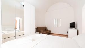 Cette chambre blanche comprend un lit et un miroir. dans l'établissement Alloggio da Paolina, à Castellaneta
