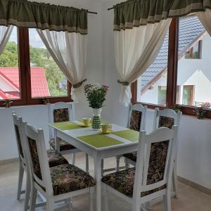 Casa Sofia في Bălţăteşti: غرفة طعام مع طاولة وكراسي ونوافذ