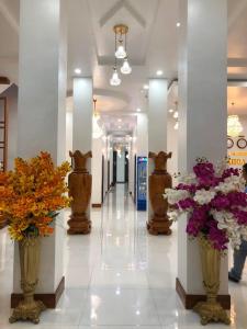 un pasillo con jarrones de flores en un edificio en HOTEL ĐĂNG KHOA 2 NÚI SAM en Chau Doc