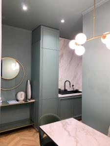 - une cuisine avec des placards gris, une table et un miroir dans l'établissement Appartement l'émeraude à Saint Malo Intra-Muros, à Saint-Malo