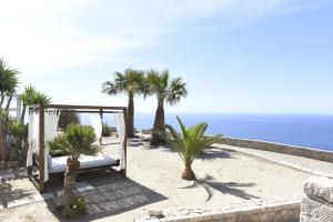 a white bed on a beach with palm trees and the ocean at Aigeis-milos in Agia Kiriaki Beach