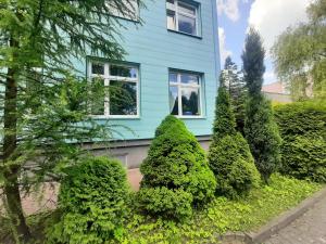 a blue house with bushes in front of it at Hotel Marco in Będzin