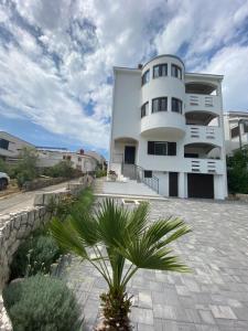een wit gebouw met een palmboom ervoor bij Apartments Mima in Petrcane
