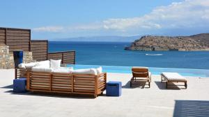 a patio with a couch and chairs next to the water at Luxury Villa Veronika in Pláka