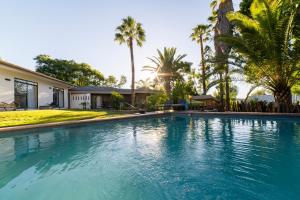 a swimming pool in front of a house with palm trees at Hotel Pension Palmquell in Klein Windhoek