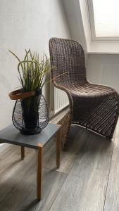 a wicker chair and a table with a potted plant at Apartments Benzweg 2 in Northeim