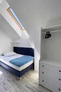 sypialnia z niebieskim łóżkiem i białą komodą w obiekcie Domki Nord Star we Władysławowie