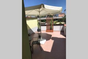 einen Tisch und Stühle mit Sonnenschirm auf dem Balkon in der Unterkunft Aperitivo in terrazza vicinissimo al centro. in Parma