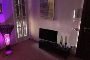 ein Wohnzimmer mit einem TV und einem lila Licht in der Unterkunft Aperitivo in terrazza vicinissimo al centro. in Parma