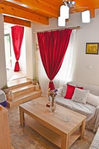 a living room with a couch and red curtains at Marilou's Cottage in Ágios Matthaíos