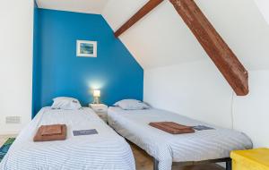 Dos camas en una habitación con una pared azul. en Holiday Normandy se ressourcer à deux pas de la Mer, en Fermanville