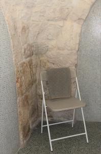 a chair sitting in front of a stone wall at Masseria La Mandra in Noci