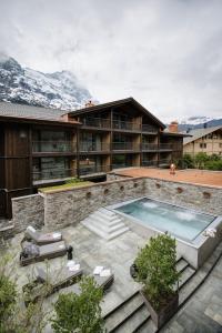 a house with a swimming pool in front of a building at Bergwelt Grindelwald - Alpine Design Resort in Grindelwald