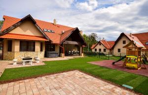 un patio trasero con un parque infantil y una casa en Bakonyi Mesekastély, en Olaszfalu