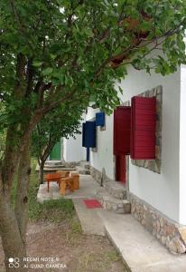 a building with red shutters and a table and a tree at La Actoru` in Vama Veche