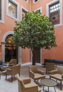 a tree in a courtyard with chairs and tables at Casa da Companhia Hotel & Spa, Vignette Collection by IHG in Porto