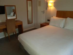 Tri-Star Hotel في برمنغهام: غرفة نوم بسرير ومكتب ومرآة