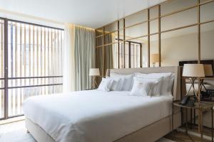 a bedroom with a large white bed and a large window at Casa da Companhia Hotel, Vignette Collection in Porto