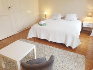 um quarto com uma cama branca e uma cadeira em Maison de ville confortable avec cour interieure em Angoulême