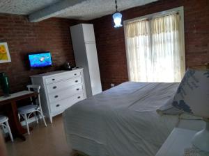 a bedroom with a bed and a desk and a television at Apartamento no Centro de Gramado in Gramado