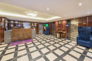 a lobby with a blue chair and a checkerboard floor at Elite Al Hamra - Al Cornich in Jeddah