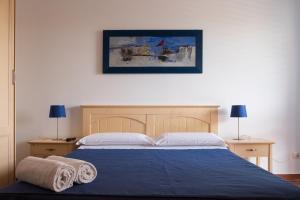 a bedroom with a blue bed with two towels on it at Orsola Apartments in Favignana