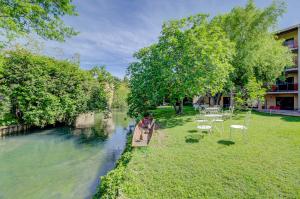 un bateau sur une rivière avec des tables et des chaises dans l'établissement Hotel Les Nevons, à LʼIsle-sur-la-Sorgue