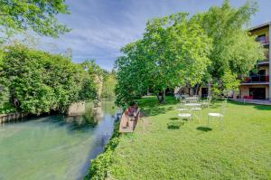 a boat on a river with tables and chairs at Hotel Les Nevons in L'Isle-sur-la-Sorgue