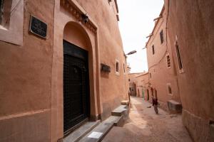 une personne marchant dans une ruelle avec une grande porte de garage dans l'établissement Dar Kamar, à Ouarzazate