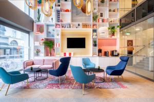 a lobby with a pink couch and blue chairs at B&B HOTEL Gent Centrum in Ghent