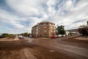 a dirt road with a building and cars parked on the street at Edificio Pampa II in Añelo