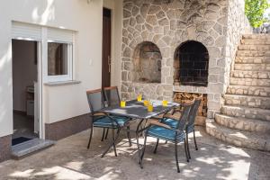 une table et des chaises sur une terrasse avec une cheminée dans l'établissement Apartments Omorfia, à Kraljevica