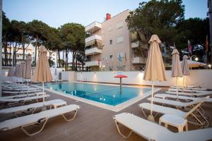 a pool with chairs and umbrellas next to a building at Hotel Kapri in Golem