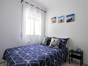 una camera da letto con un letto con un piumone blu e una finestra di Conil Centro & Playa, descanso perfecto, Aire Ac y WIFI -SOLO FAMILIAS Y PAREJAS- a Conil de la Frontera