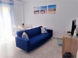 a blue couch in a living room with a tv at Conil Centro & Playa, descanso perfecto, Aire Ac y WIFI -SOLO FAMILIAS Y PAREJAS- in Conil de la Frontera