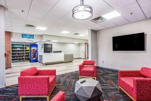 a waiting room with red chairs and a flat screen tv at Clarion Pointe Franklin - Nashville Area in Franklin