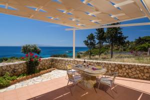 un patio con mesa, sillas y el océano en Asta La Vista Maisonettes, en Pesádha