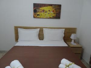 ein Bett mit weißen Kissen und ein Gemälde an der Wand in der Unterkunft B&B DODO in Salerno