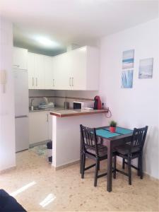 a kitchen with white cabinets and a table and chairs at Apartamento Conil Playa & Centro, perfecto descanso, con Aire Acond y WIFI in Conil de la Frontera