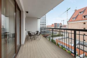 uma varanda com cadeiras e uma mesa num edifício em Grand Apartments - Davos Apartment Gdańsk Szafarnia River View em Gdansk
