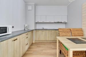 cocina con armarios de madera, mesa y microondas en Grand Apartments - Davos Apartment Gdańsk Szafarnia River View, en Gdansk