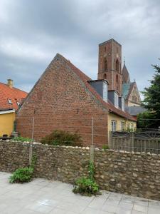 un edificio de ladrillo con una pared de piedra y una torre en Præstegade 11 en Ribe