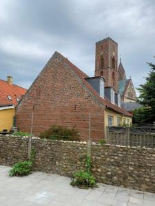 a brick building with a stone wall and a tower at Præstegade 11 in Ribe