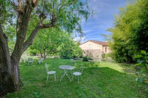 a table and chairs in a yard with a tree at Hotel Les Nevons in LʼIsle-sur-la-Sorgue