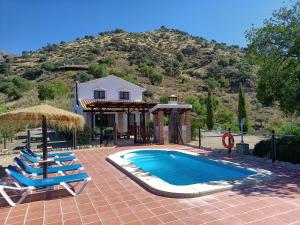 una piscina con 2 tumbonas y una casa en Casita la Herilla, en El Chorro