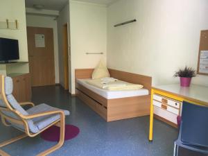 une chambre avec un lit, une chaise et un bureau dans l'établissement Gästehaus Goethe-Institut Schwäbisch Hall, à Schwäbisch Hall