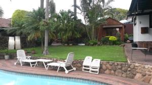 a group of chairs and tables next to a pool at Smiths Cottage in Durban