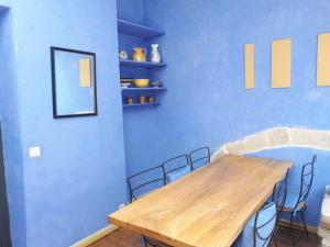 ein Esszimmer mit einem Holztisch und blauen Wänden in der Unterkunft Appartement au coeur du village- Ref12 in Saint-Paul-Trois-Châteaux
