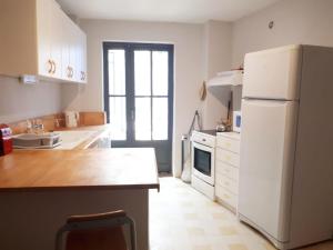 eine Küche mit einem weißen Kühlschrank und einem Tisch in der Unterkunft Appartement au coeur du village- Ref12 in Saint-Paul-Trois-Châteaux